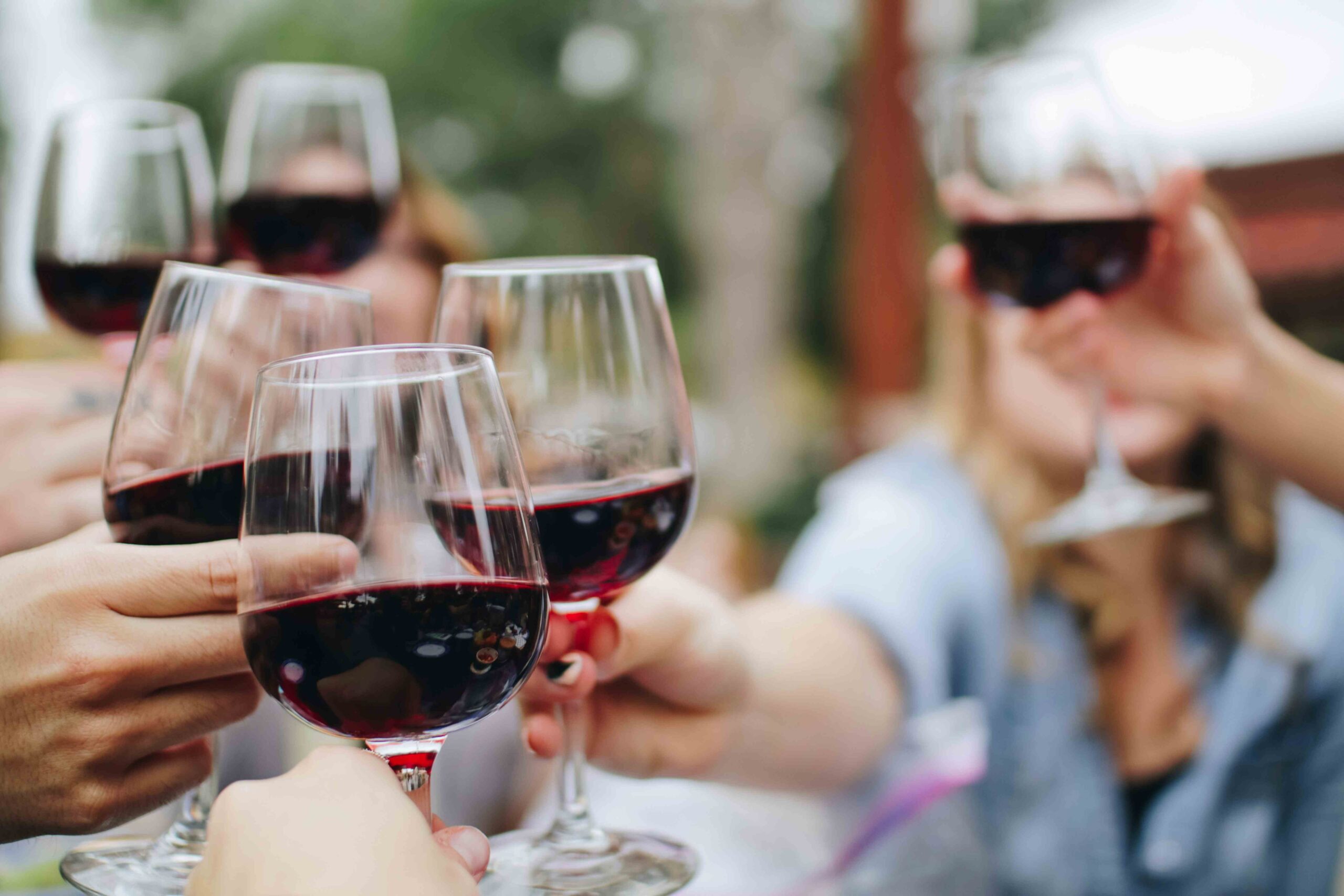 Group of friends holding up full wine glasses together on a day out